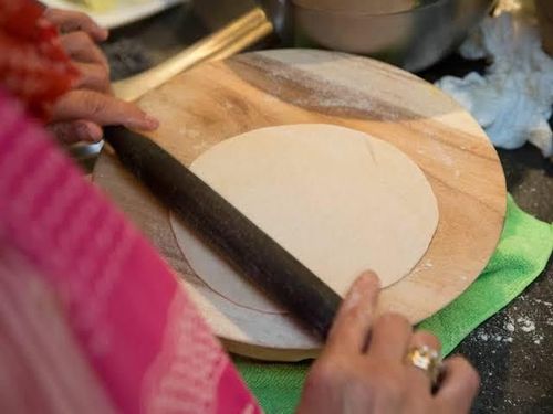 Traveler rolling roti dough during a hands-on vegetarian cooking class in Jaipur